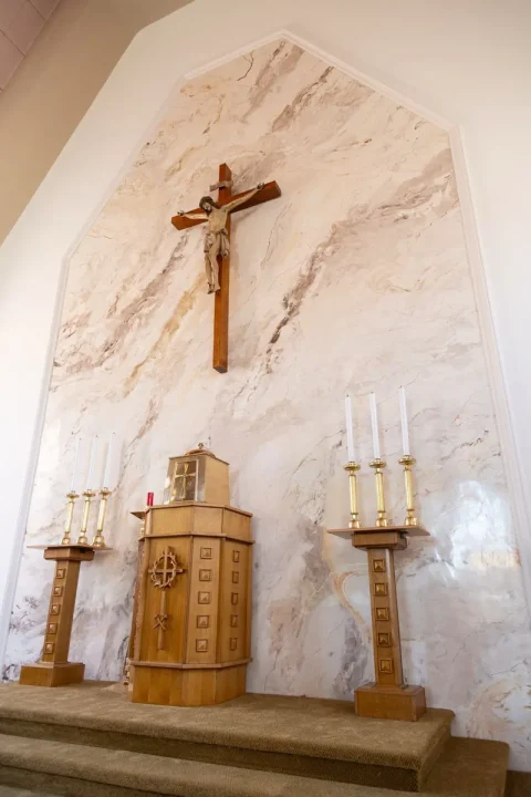 The sanctuary wall of a church behind the altar and crucifix, finished in cream, rose and grey marble-effect Venetian plaster