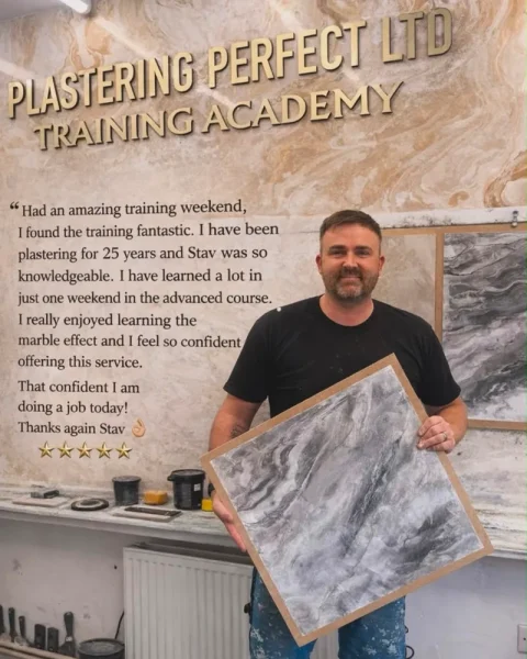 A trainee holding a grey marble-effect sample board, beside his five-star review: “Had an amazing training weekend, I found the training fantastic. I have been plastering for 25 years and Stav was so knowledgeable. I have learned a lot in just one weekend in the advanced course. I really enjoyed learning the marble effect and I feel so confident offering this service. That confident I am doing a job today! Thanks again Stav.”